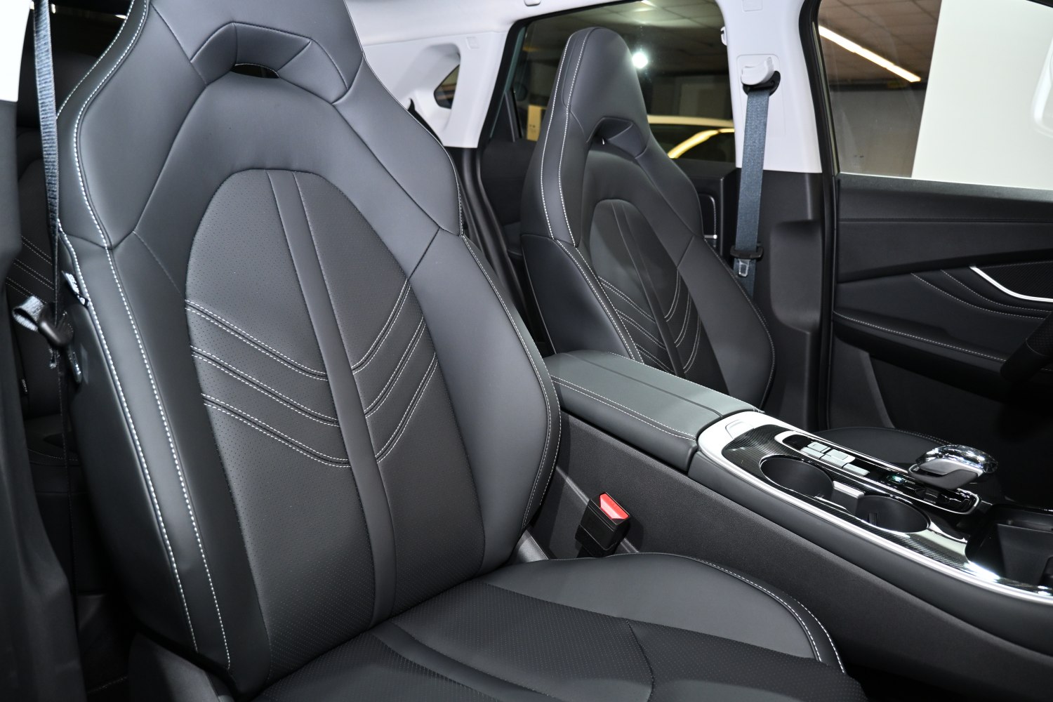 Premium black leather seats with white stitching and center console.