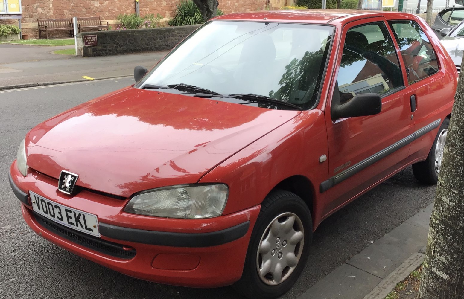 Red compact hatchback with Peugeot front design and integrated bumpers