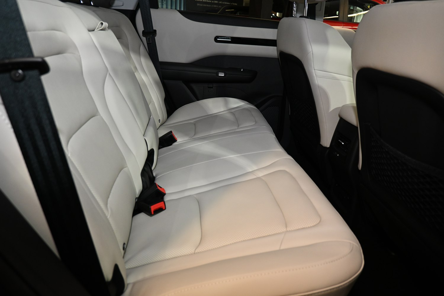 Beige leather rear seats with detailed stitching and seatbelts