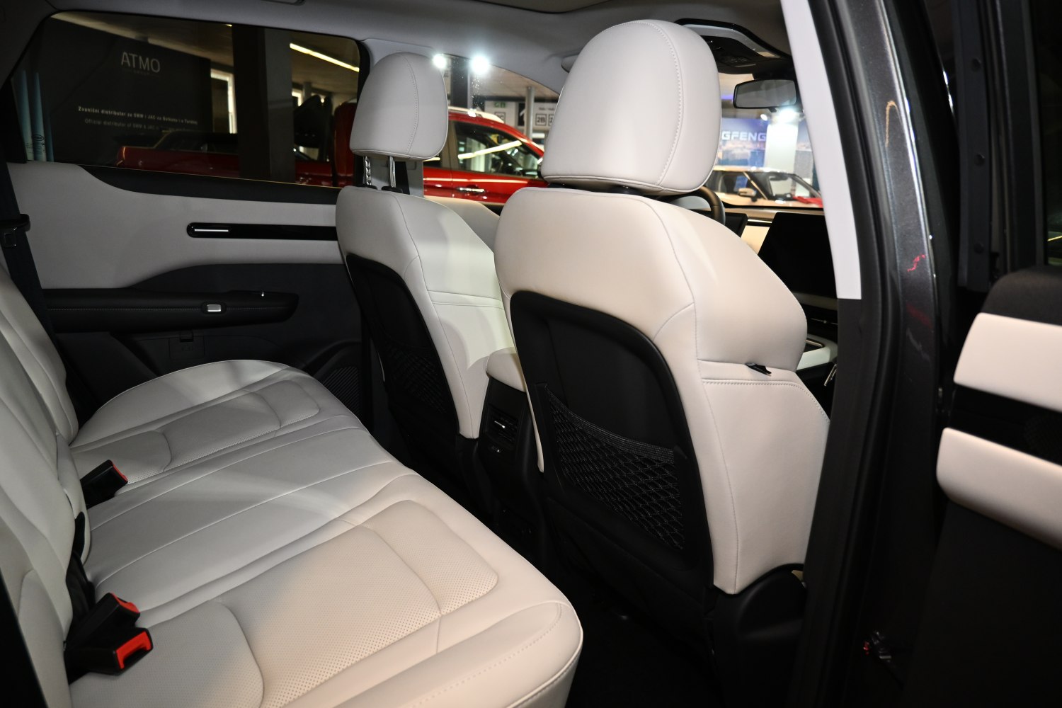 Spacious rear seats with light leather upholstery and storage nets on seat backs.