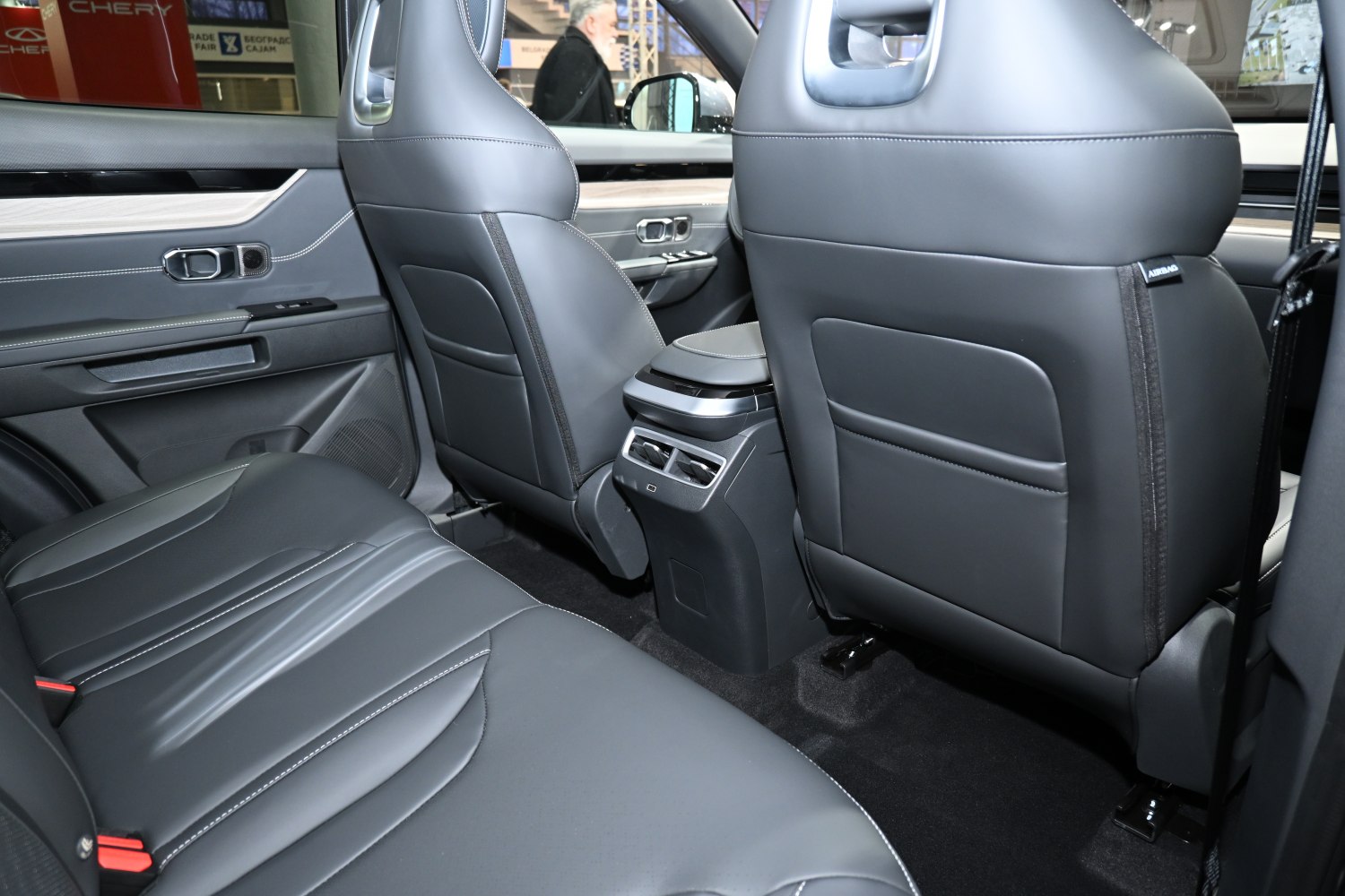 Rear black leather seats and central air vents in a car