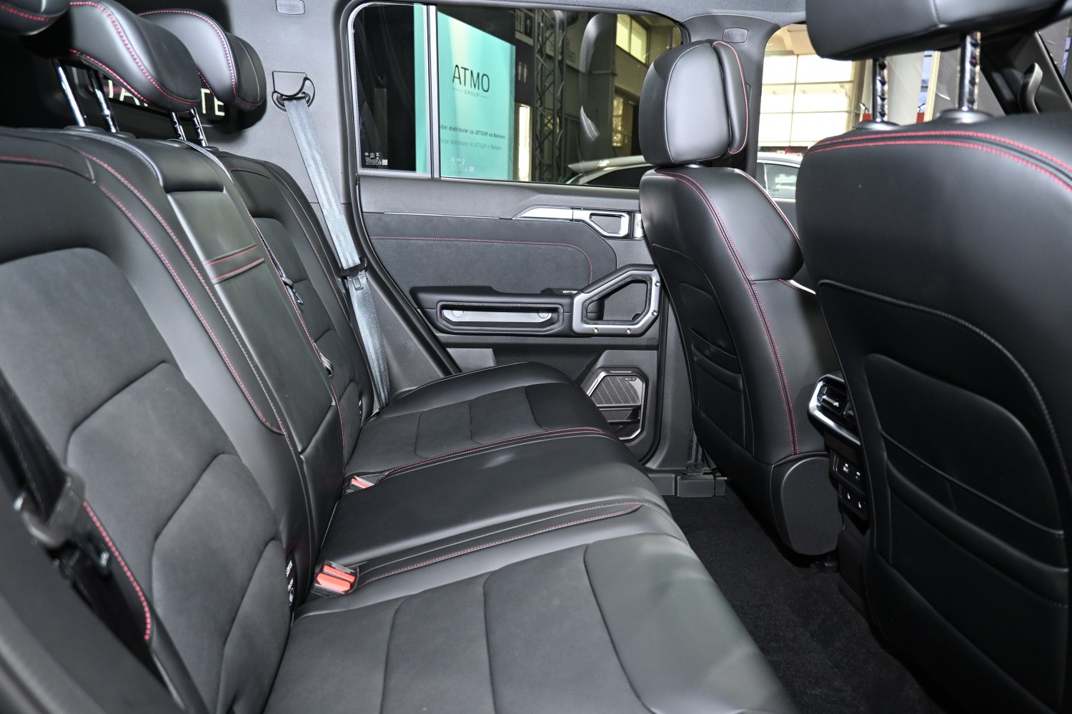 Rear black leather seats with red stitching inside a vehicle