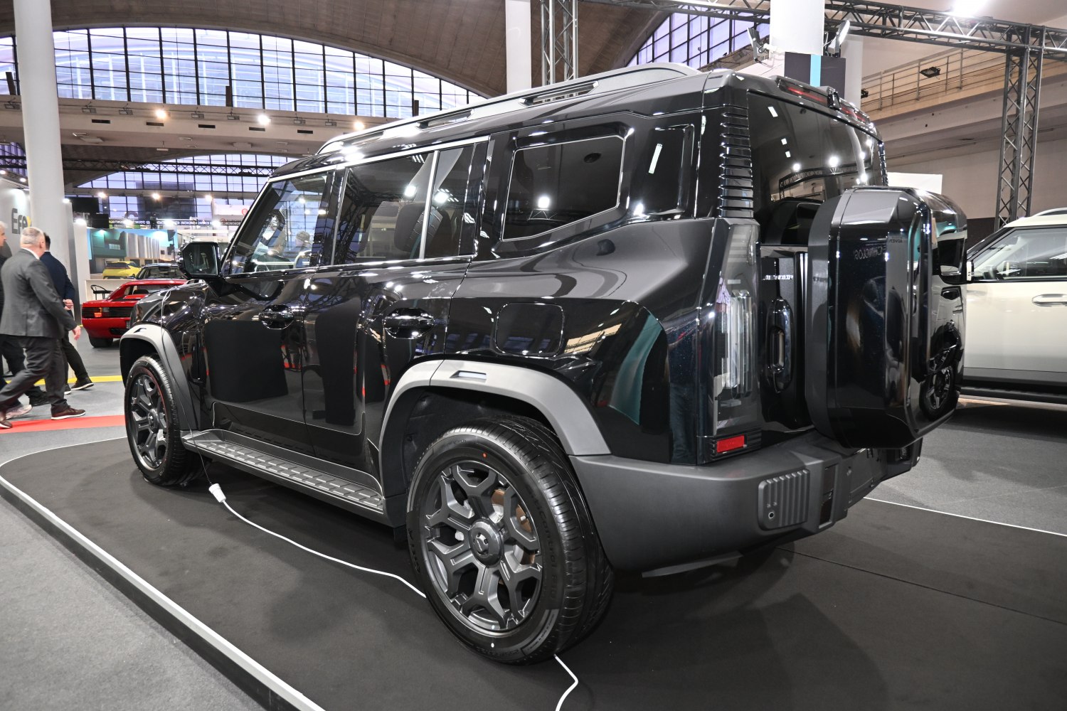 Rear side view of a black SUV with spare tire mount and electric charging cable