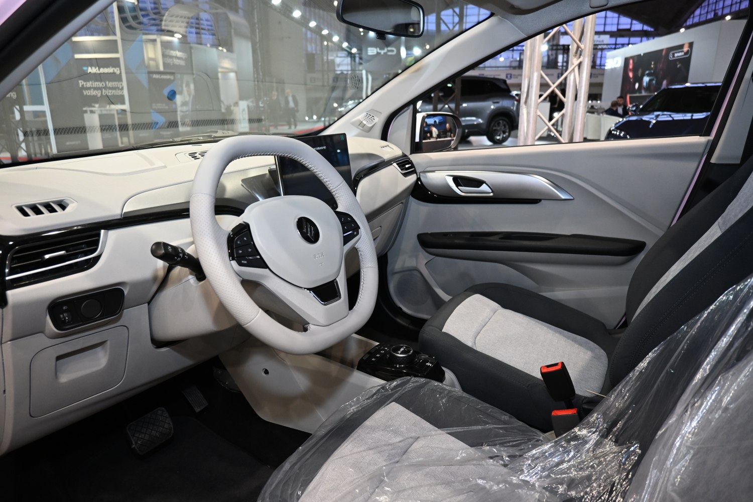 Modern electric car interior with steering wheel, touchscreen, and fabric seats