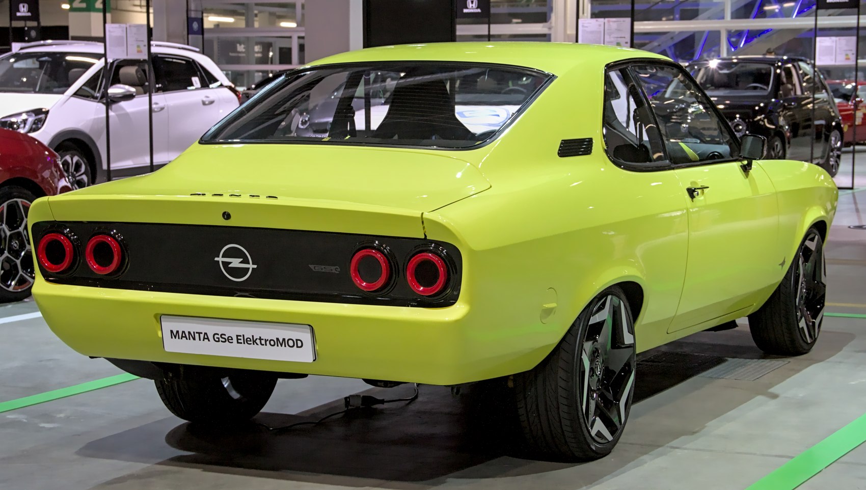 Bright lit coupe rear with circular red taillights and modern wheels