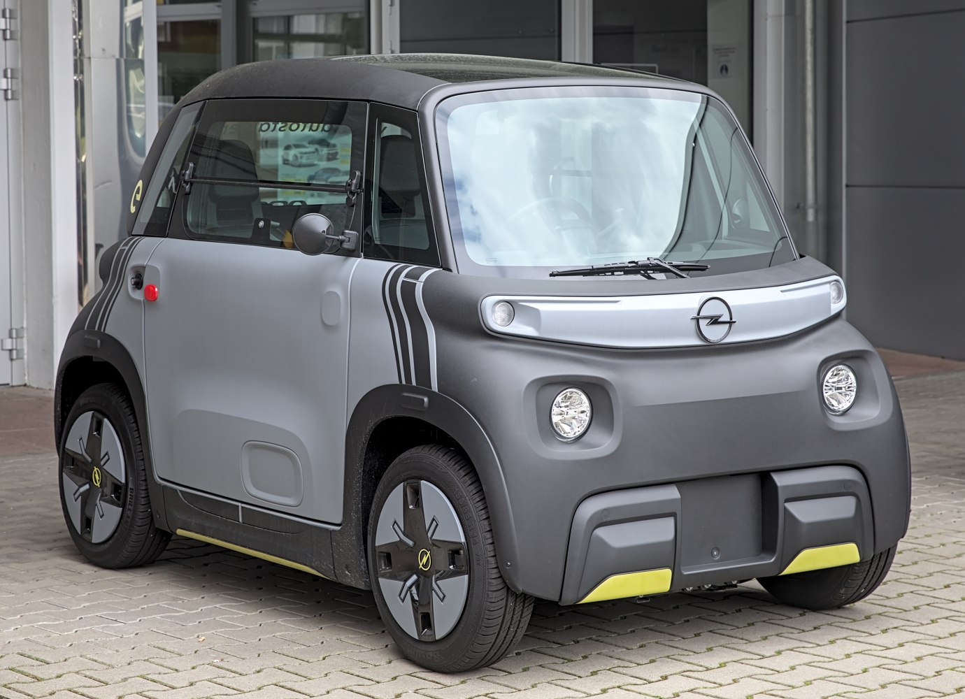 Compact electric urban vehicle with distinctive front lights and wheel design