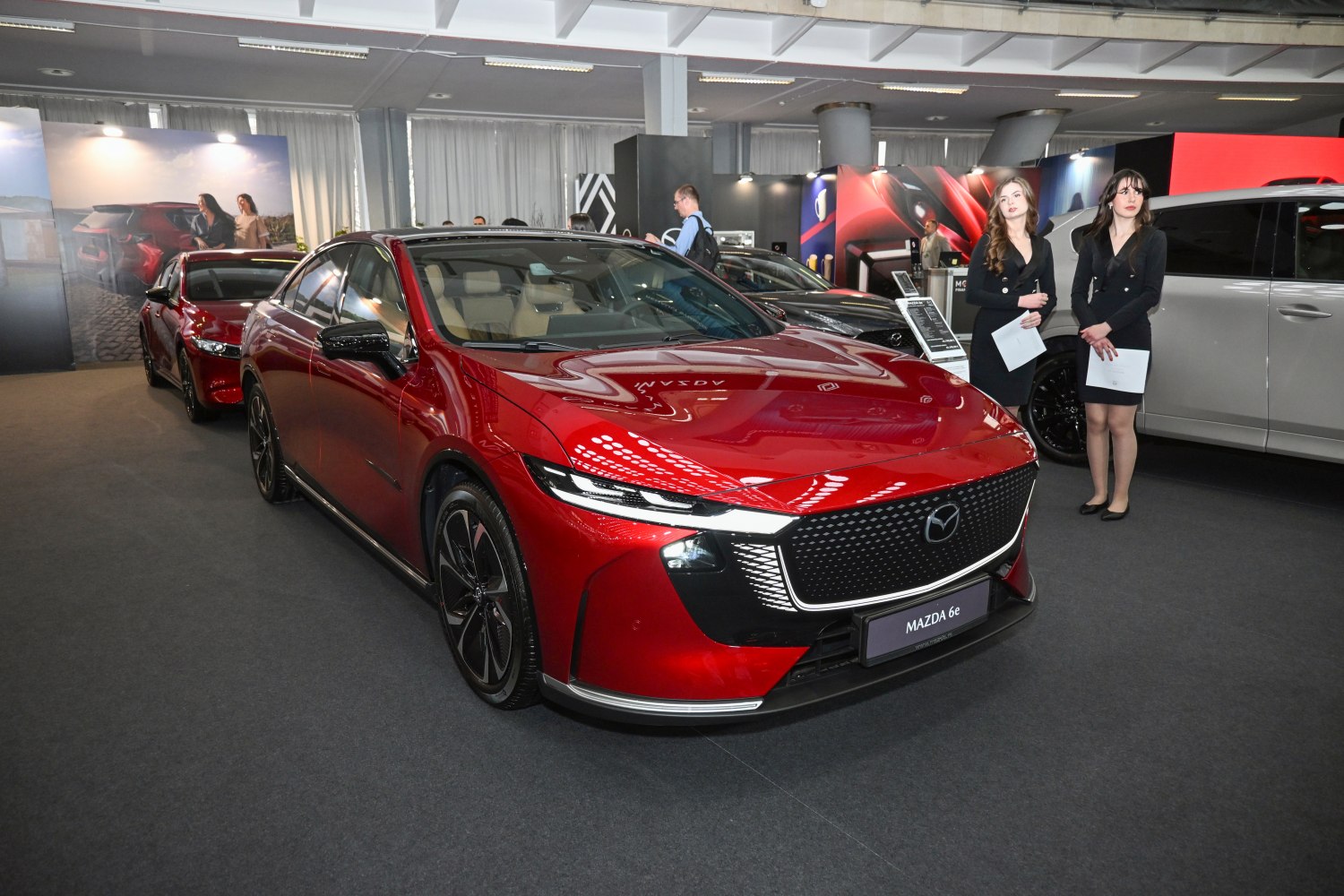 Sleek red electric sedan with illuminated grille and sharp headlights