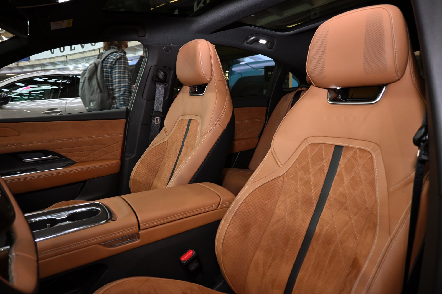 Brown leather car seats with stitching and central armrest