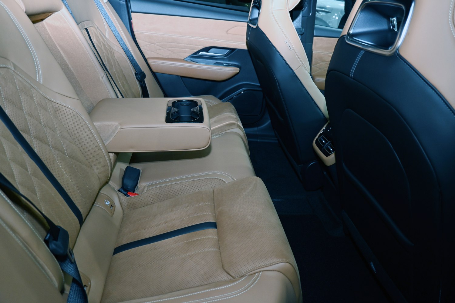 Rear tan leather seats with quilted pattern and fold-down armrest with cup holders