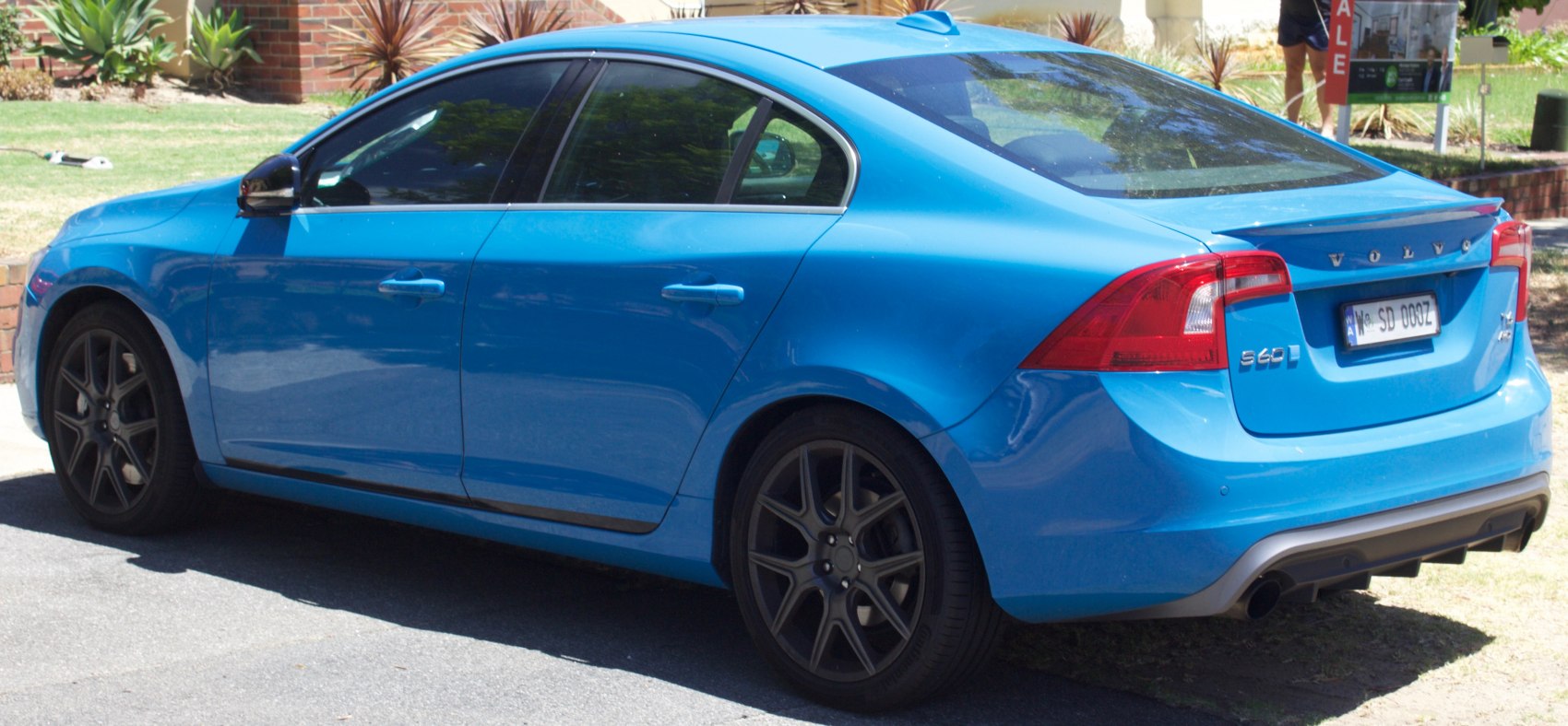 Rear side view of blue sedan with taillights and sporty alloy wheels