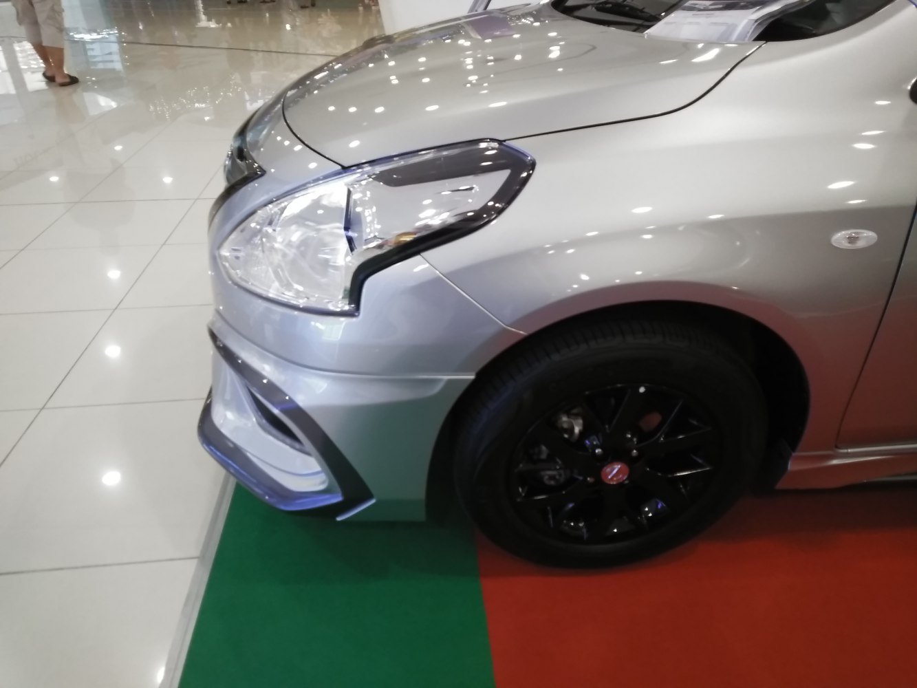Close-up of car front headlight and black alloy wheel