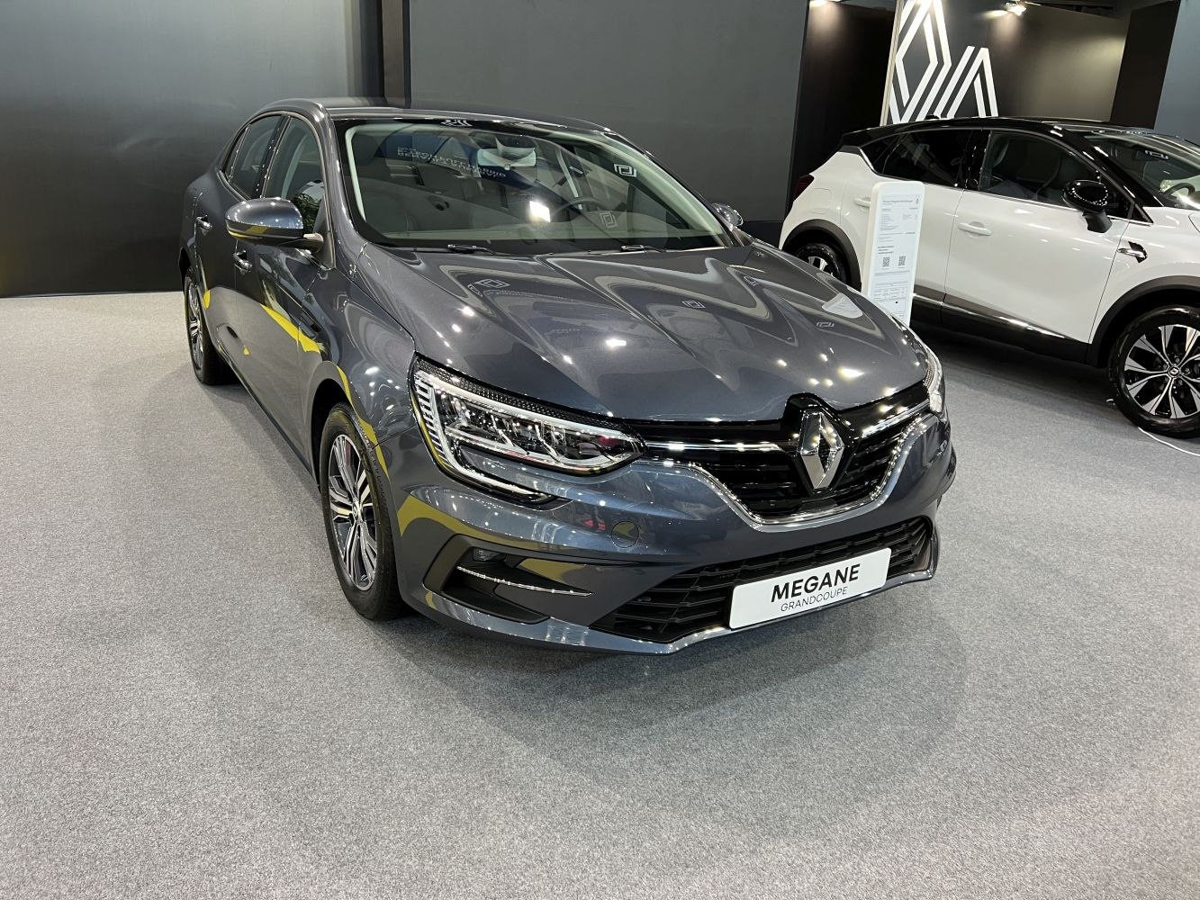 Front view of a sleek grey sedan with LED headlights and modern grille