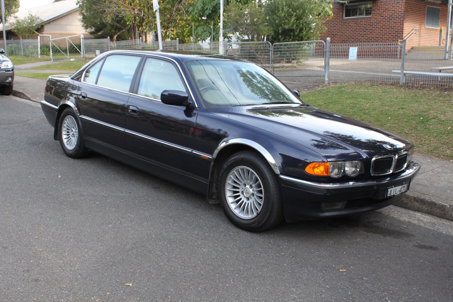 Front-side view of a dark-colored long sedan with alloy wheels and classic BMW design