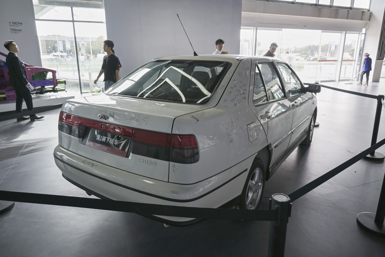 Rear view of a white sedan with tinted taillights and roof antenna
