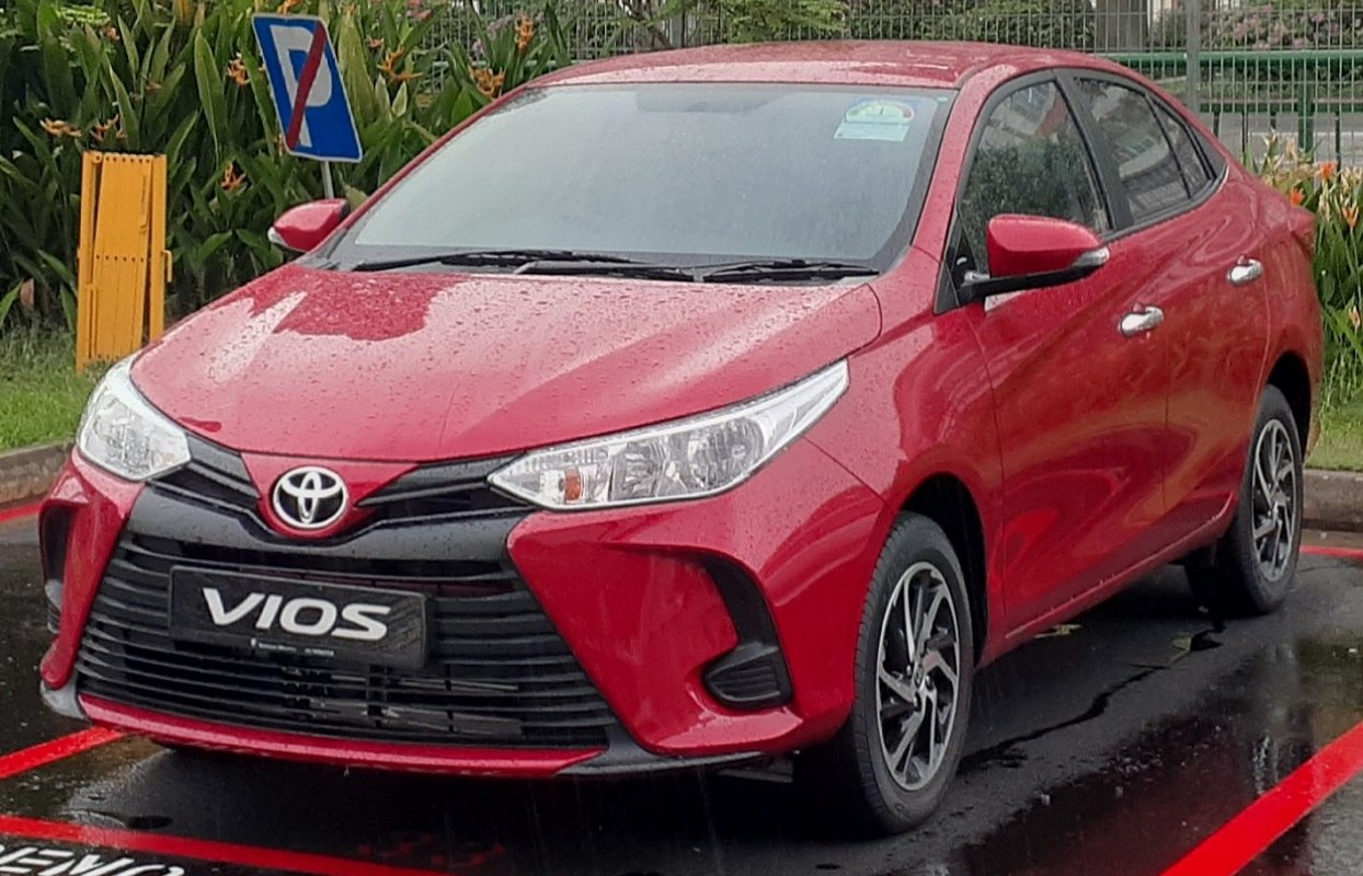 Red compact sedan front with sleek headlights and bold grille