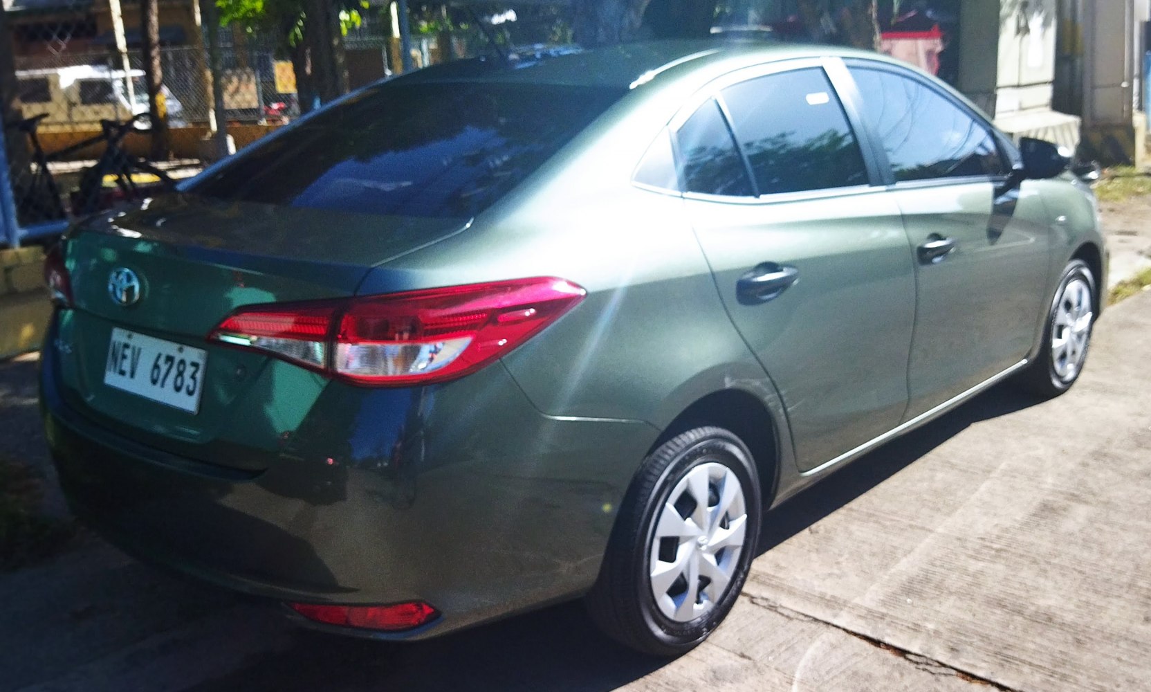 Rear side view of a green sedan with prominent taillights and tinted windows