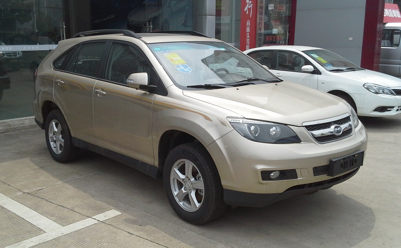 Front side view of beige SUV with roof rails and prominent headlamps