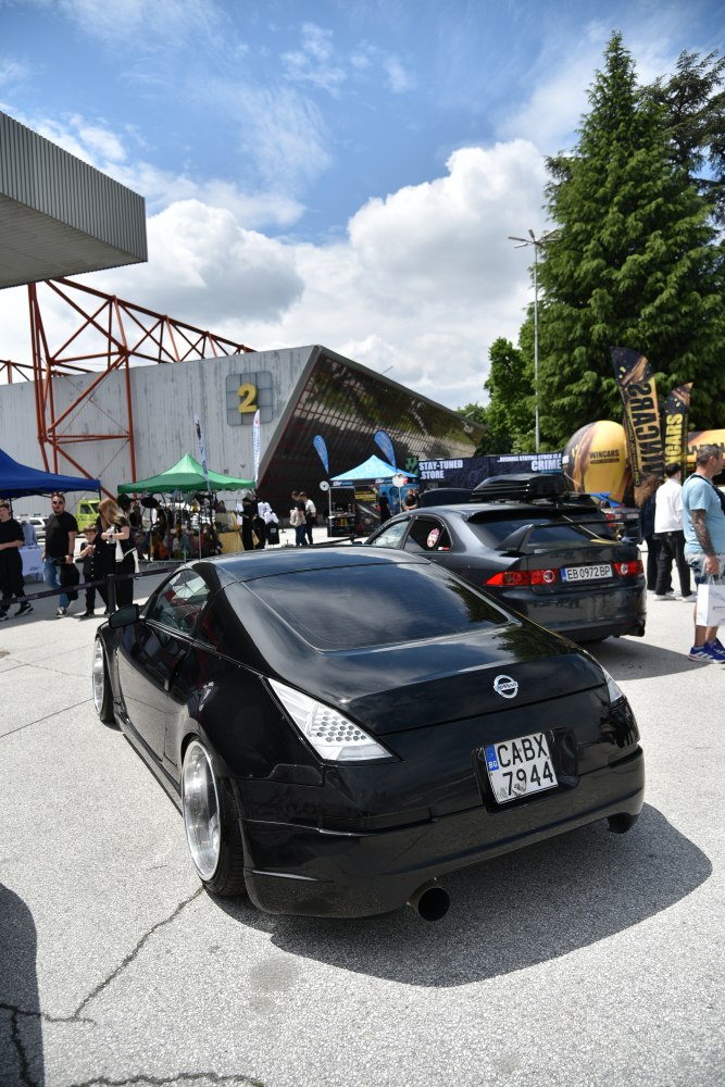 Black coupe with triangular taillights and wide custom wheels.