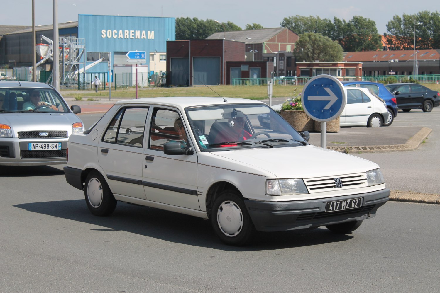 White vintage sedan front-side view driving near a roundabout