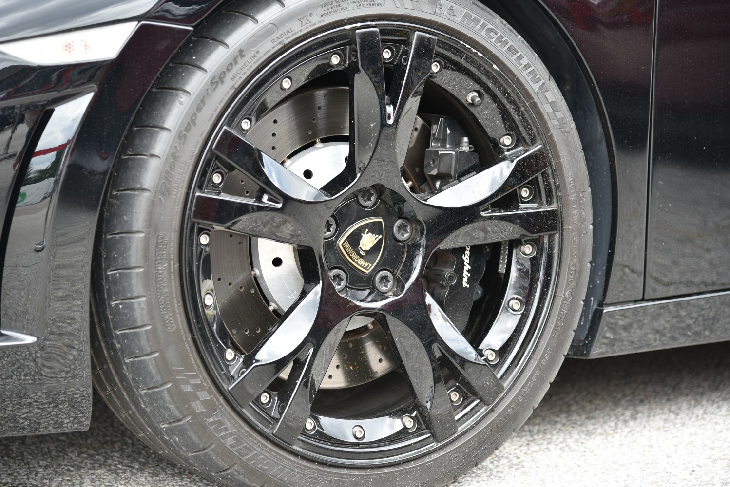 Glossy black alloy wheel with branded brake caliper and ventilated disc brake