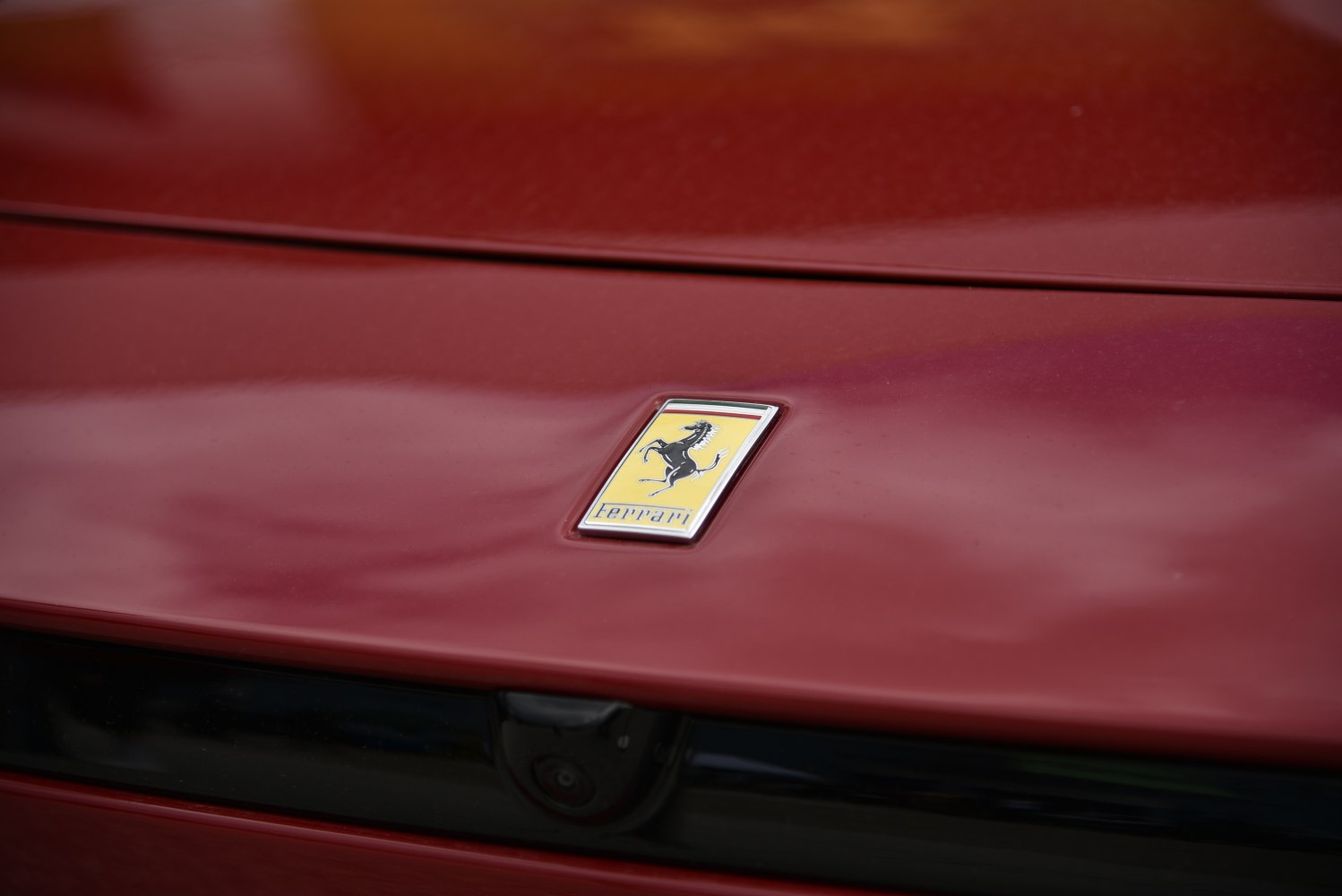 Close-up of Ferrari prancing horse emblem on red car hood
