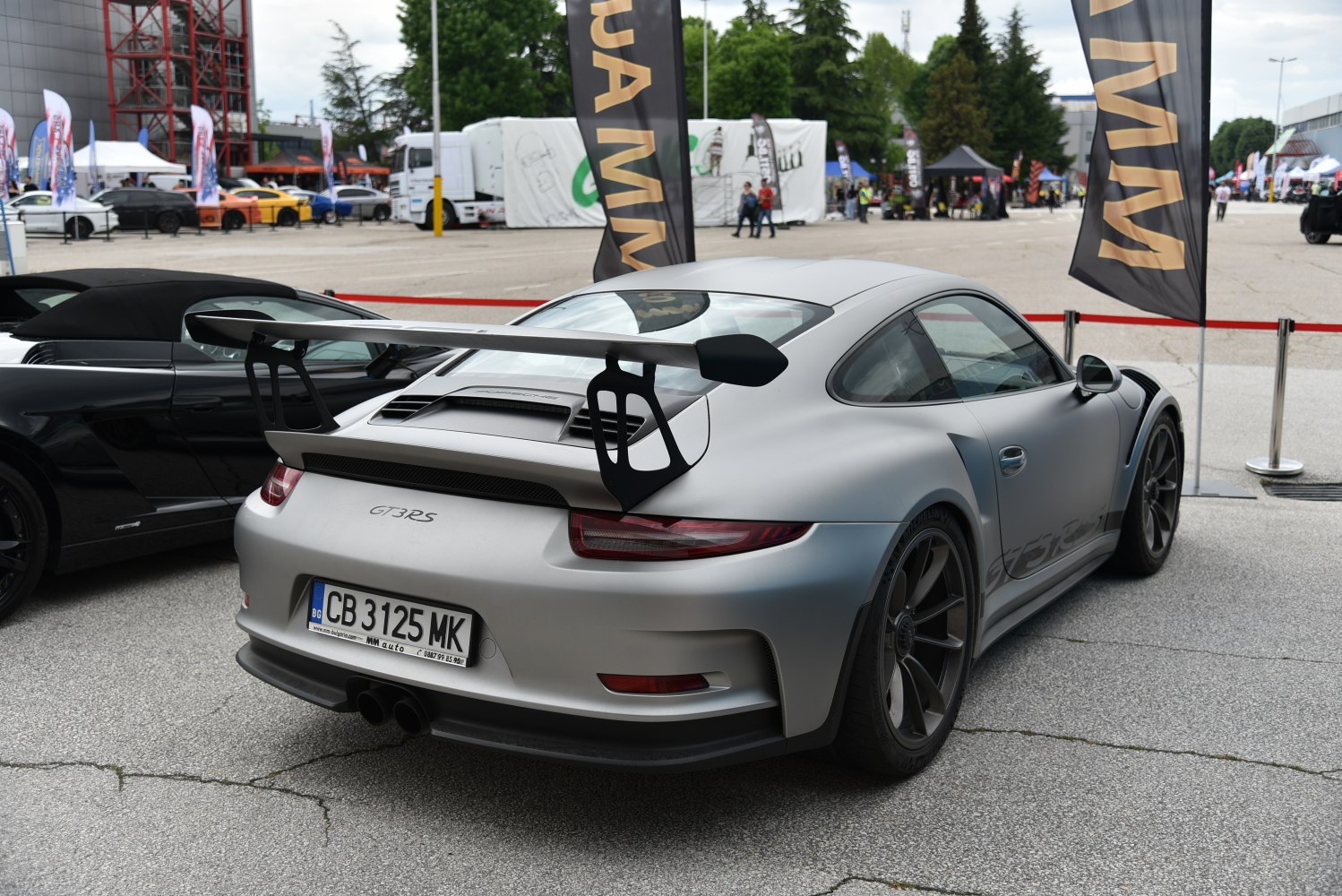 Rear of a matte silver sports coupe with large fixed rear wing