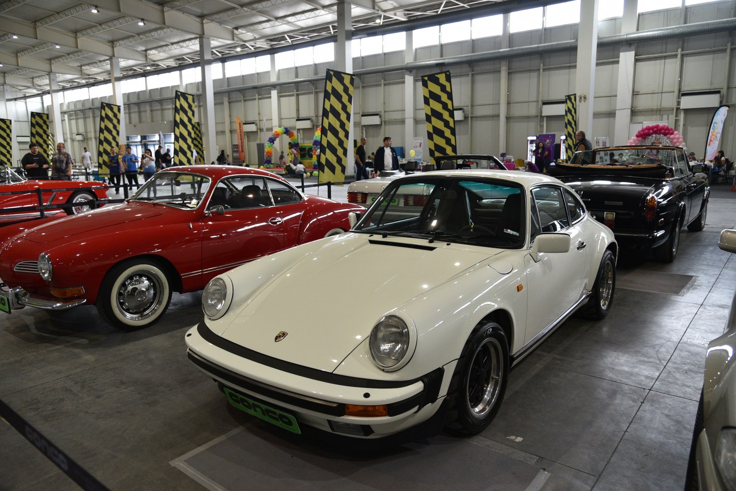 Front and side profile of classic 911 coupe, round headlights, showroom setting