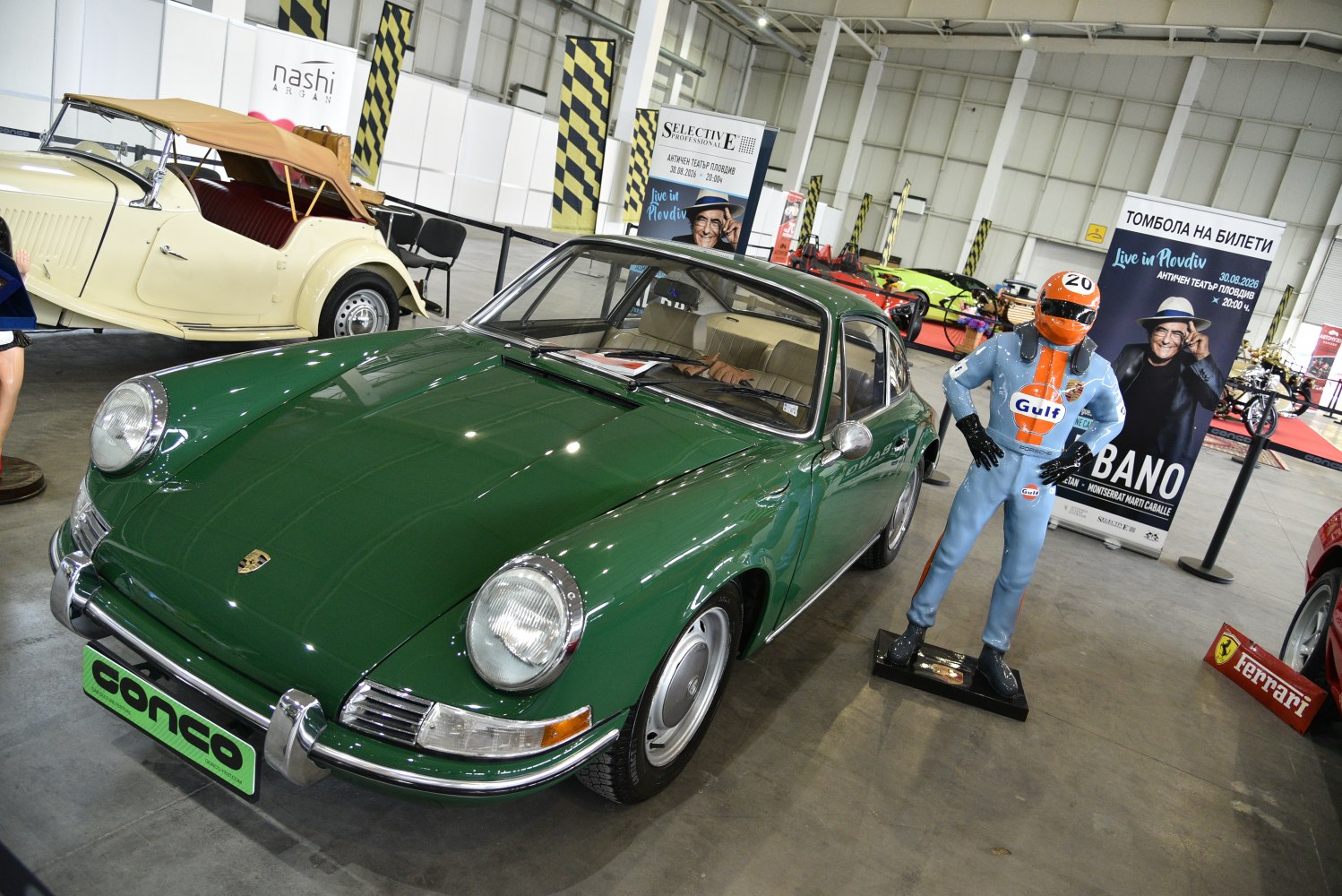 Vintage green two-door coupe with round headlights and chrome bumpers indoors