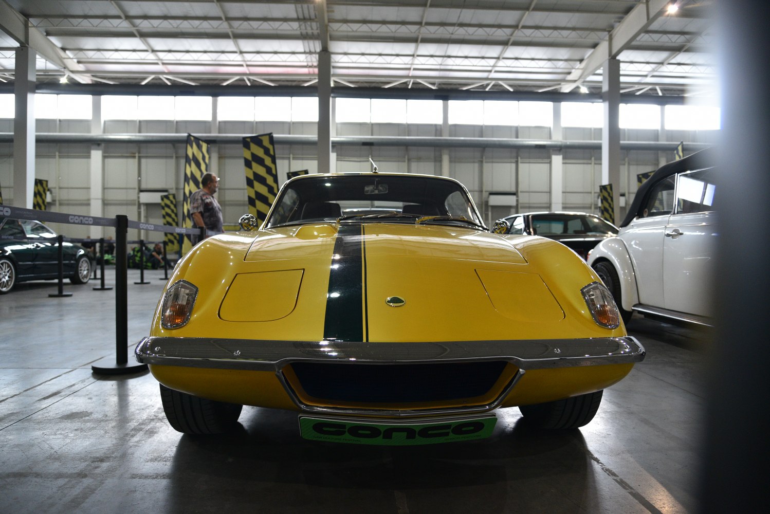 Front view of yellow sports coupe with black racing stripe and pop-up headlights
