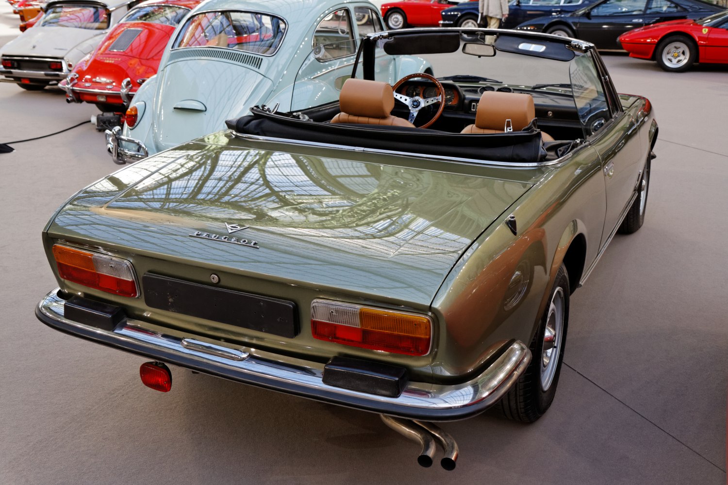 Rear view of a vintage convertible with dual exhaust and tan leather seats