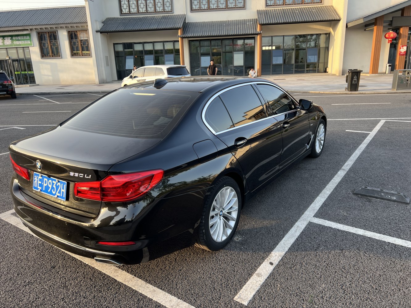 Rear and side profile of a black sedan with tinted windows and alloy wheels.