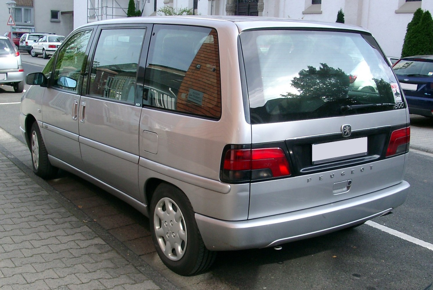 Rear and side view of a minivan with large windows and red taillights
