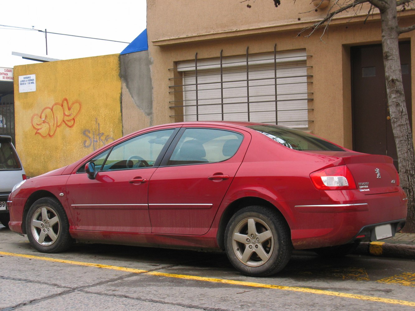 Red sedan side profile with alloy wheels and elongated roofline.