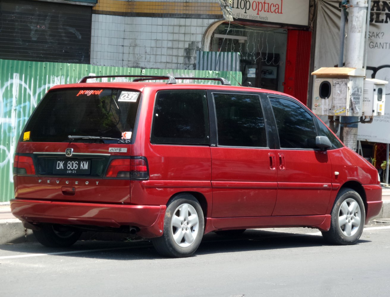 Red minivan rear-side view with roof rails and sliding doors