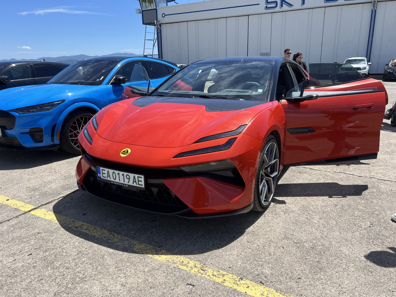 Red sports sedan front with LED headlights and open left door