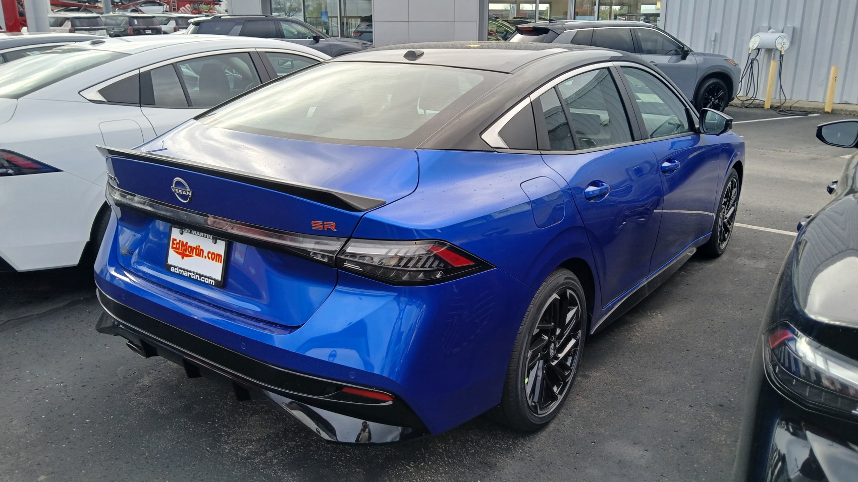 Rear and side view of blue sporty sedan with black roof and spoiler