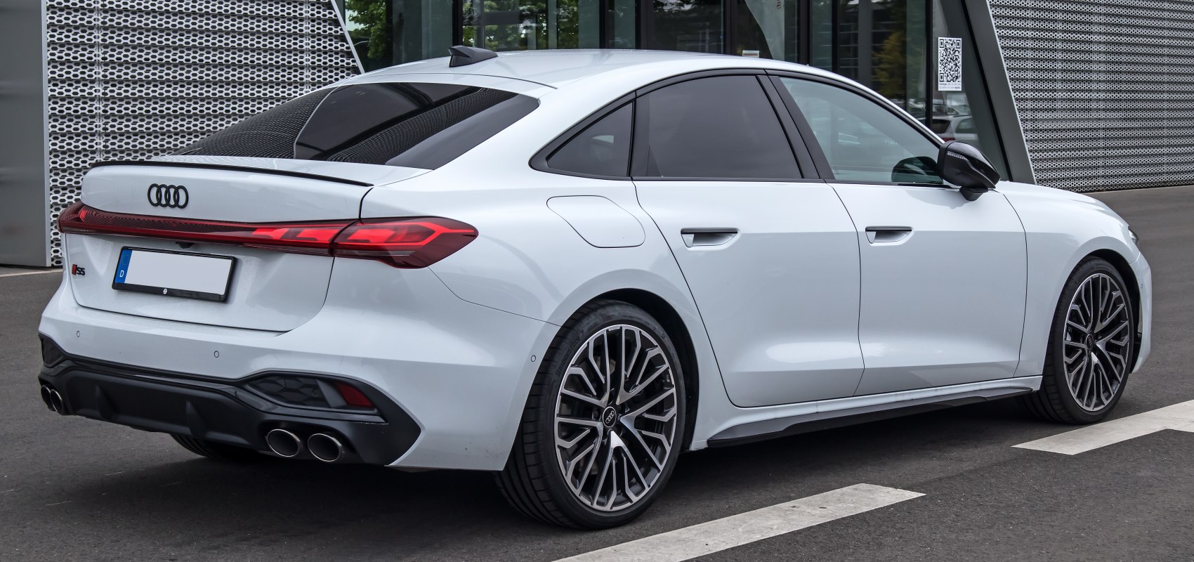 Rear side view of a sedan with quad exhaust and sporty alloy wheels