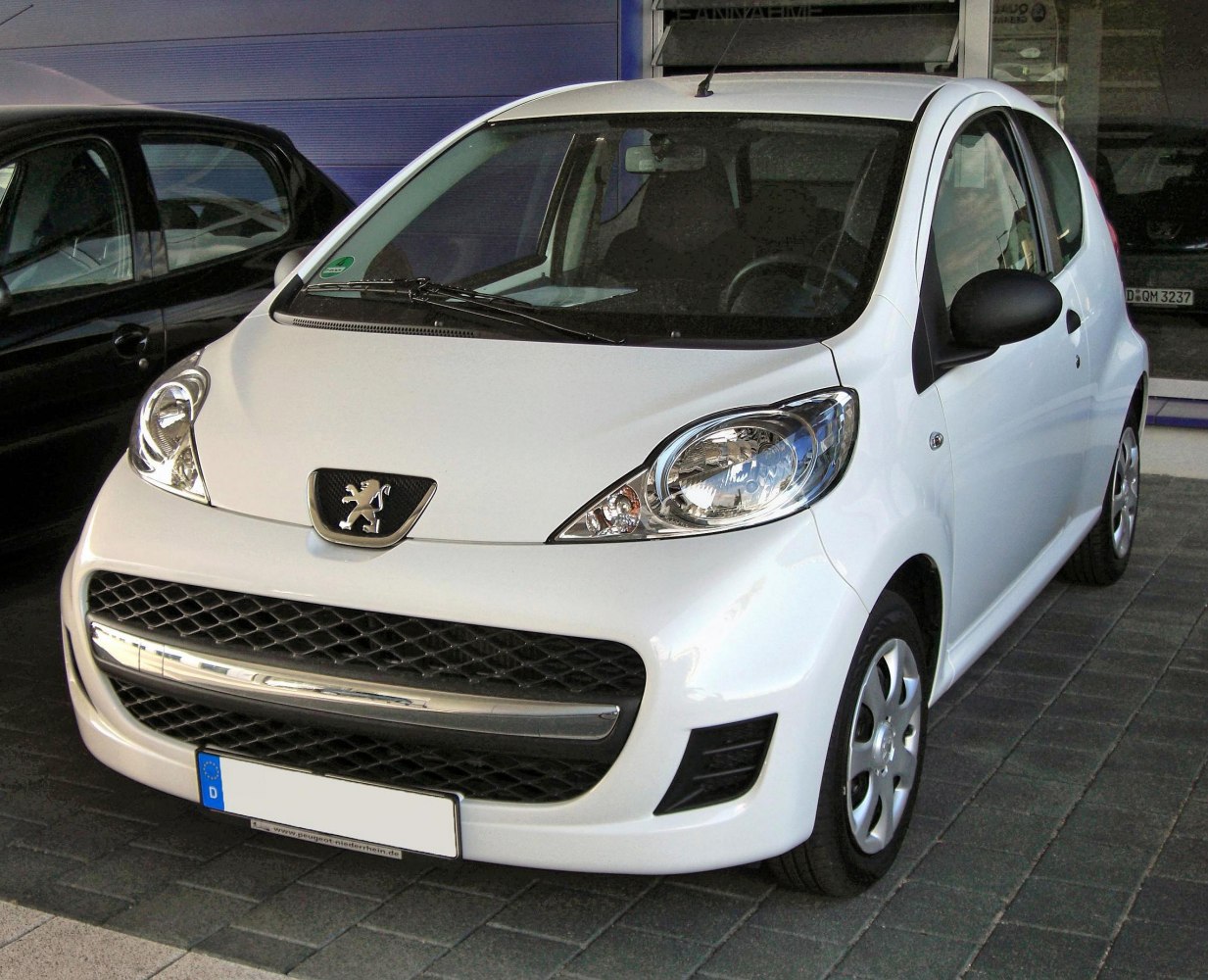 Front view of a white 3-door compact hatchback with distinct headlights and grille.