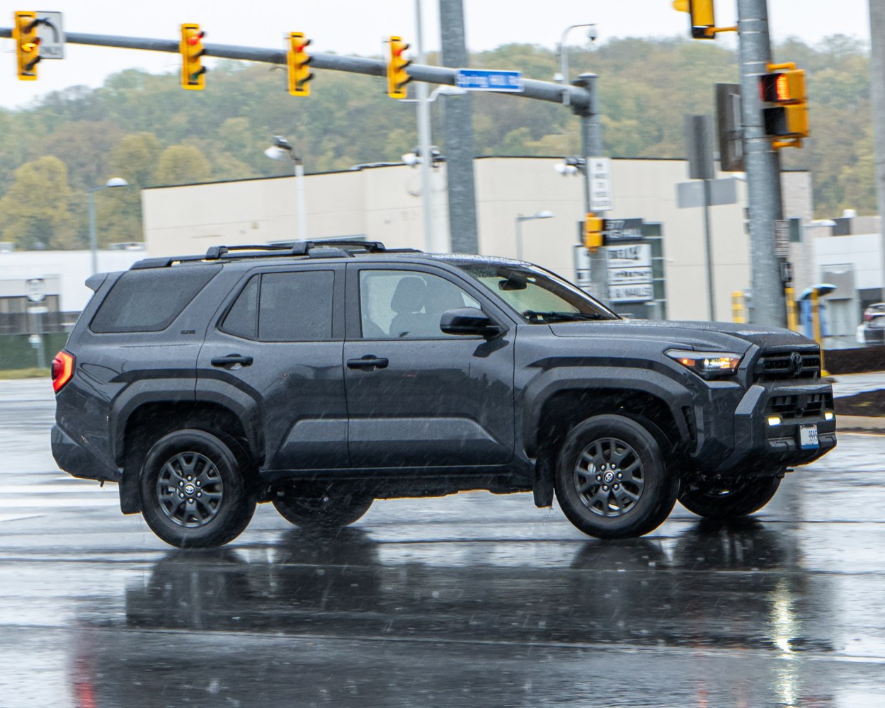 Black SUV with rugged off-road design and roof rails on wet road