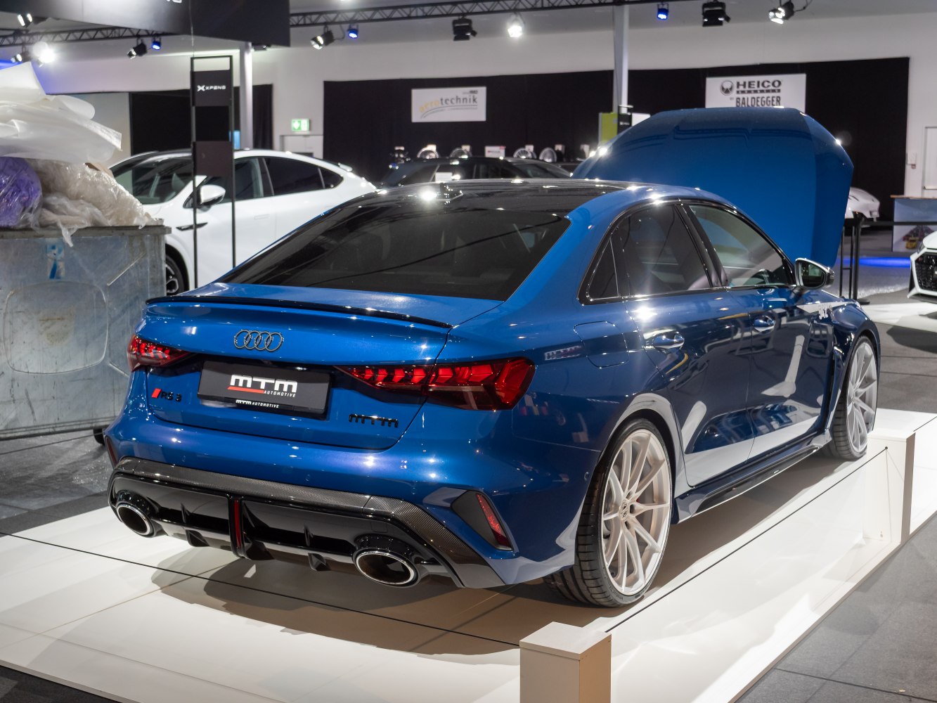 Rear view of a blue sedan with quad exhaust pipes and sporty design