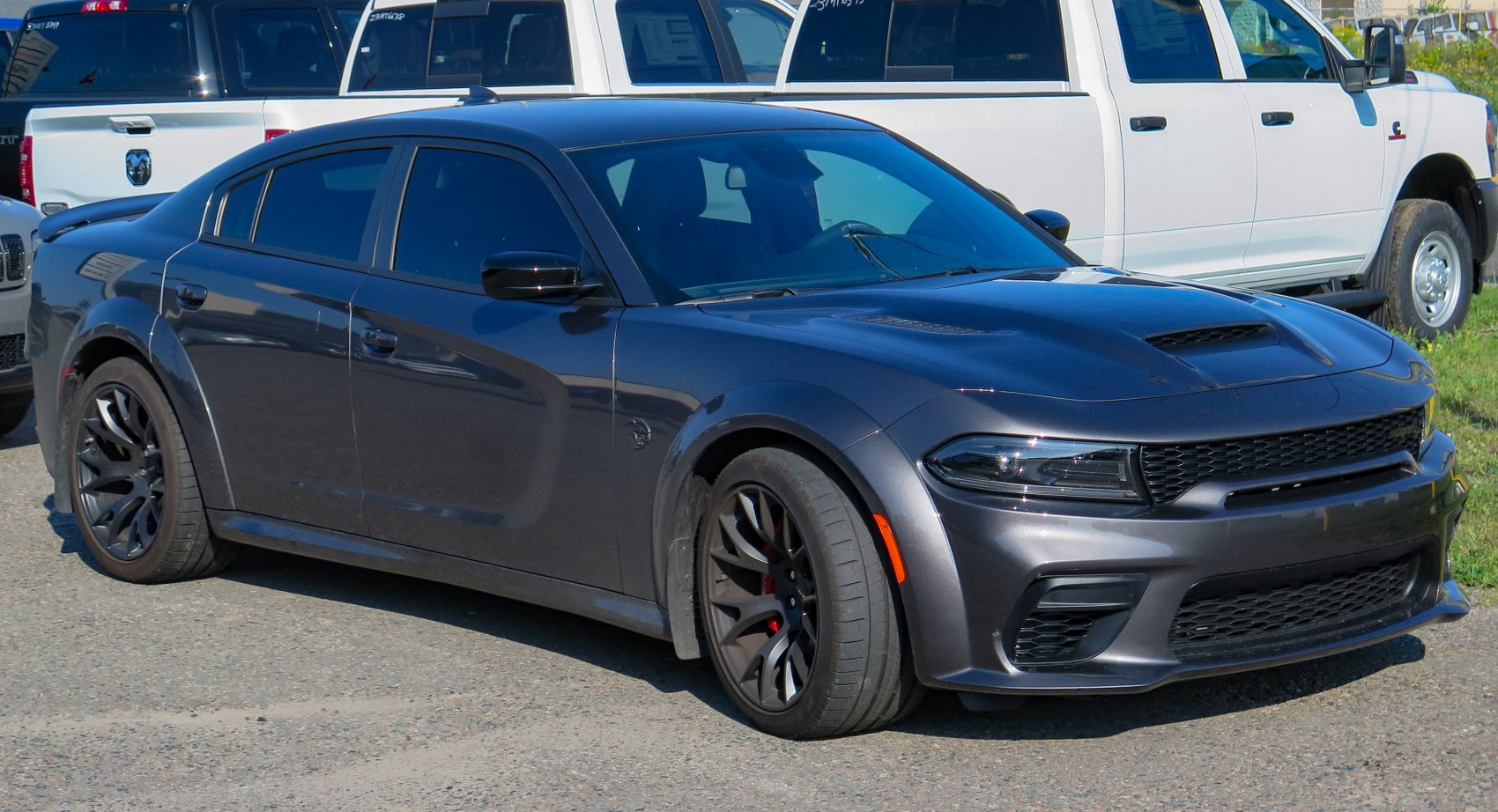 Widebody muscle sedan with sculpted hood and black alloy wheels