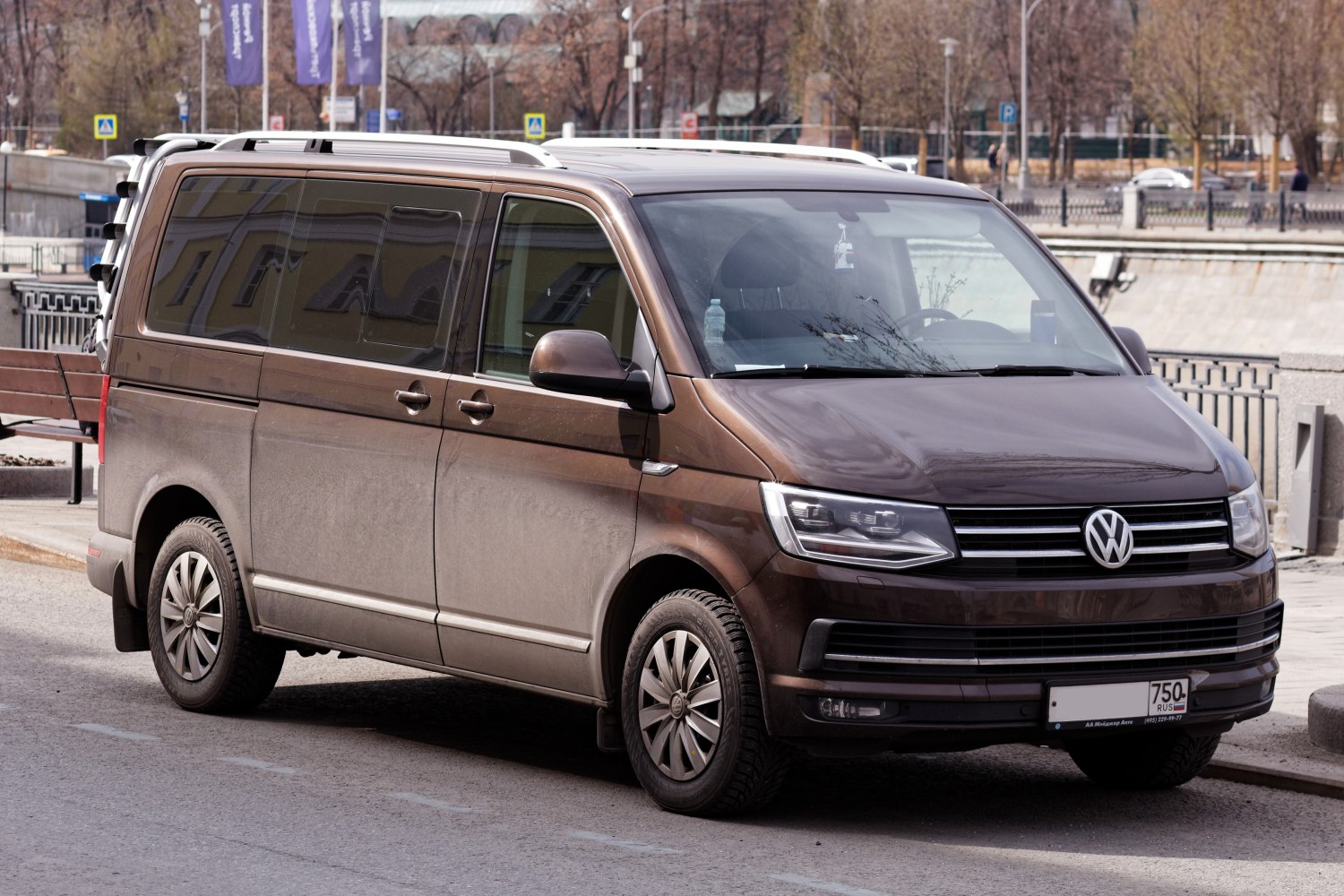 Front side view of a brown multi-purpose van with tinted windows and modern headlights