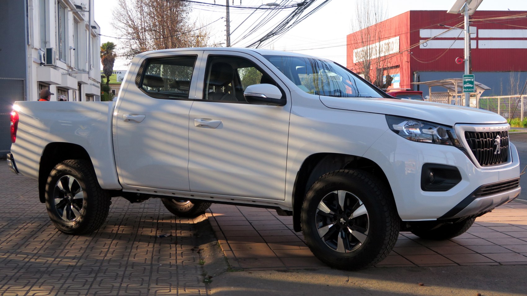 Side view of white four-door pickup truck with rugged tires