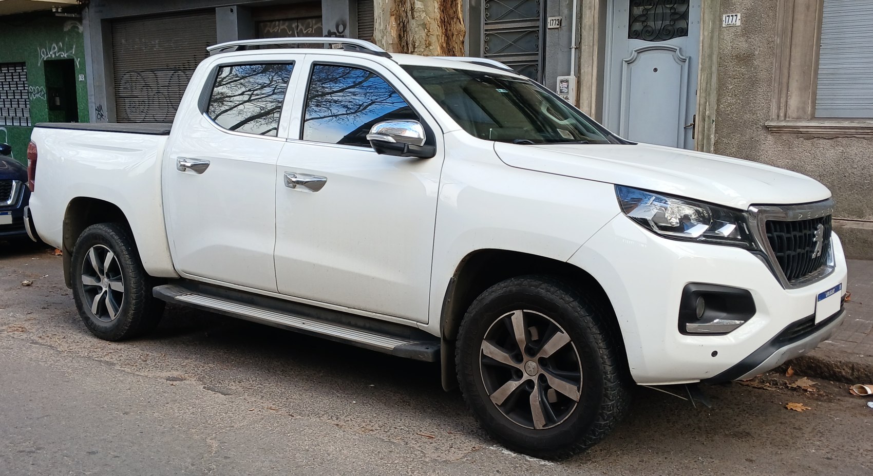 Front-side view of double cab pickup with rugged tires and chrome mirrors