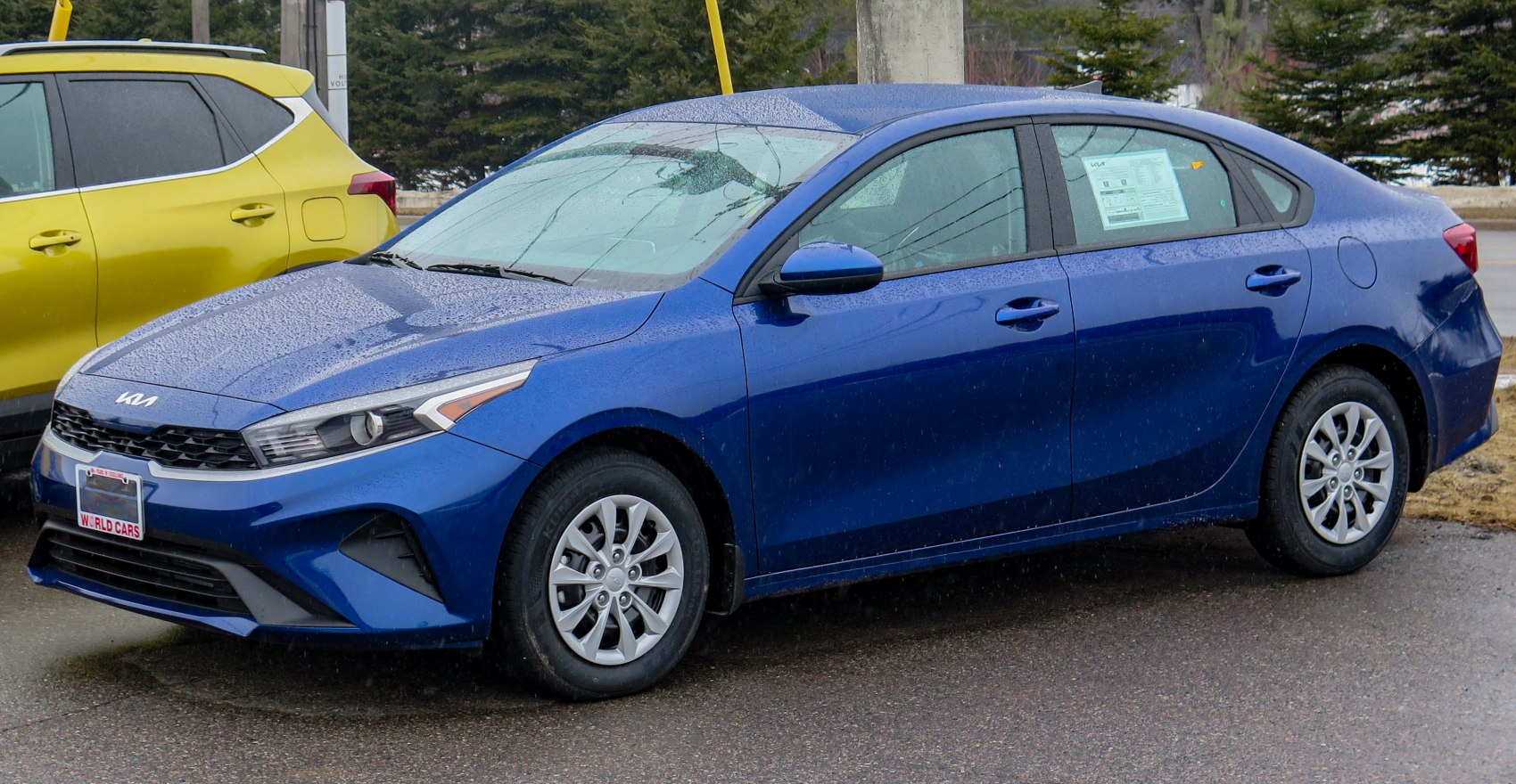 Blue sedan with modern headlights and alloy wheels viewed from front-side.