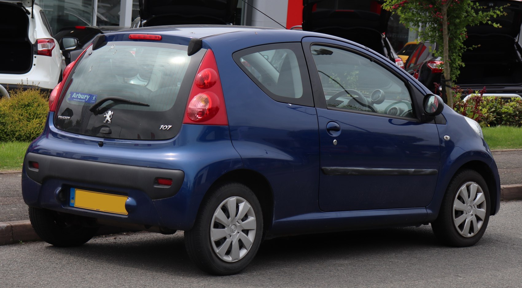 Rear side view of a blue compact 3-door hatchback with tall tail lamps and black bumper trim
