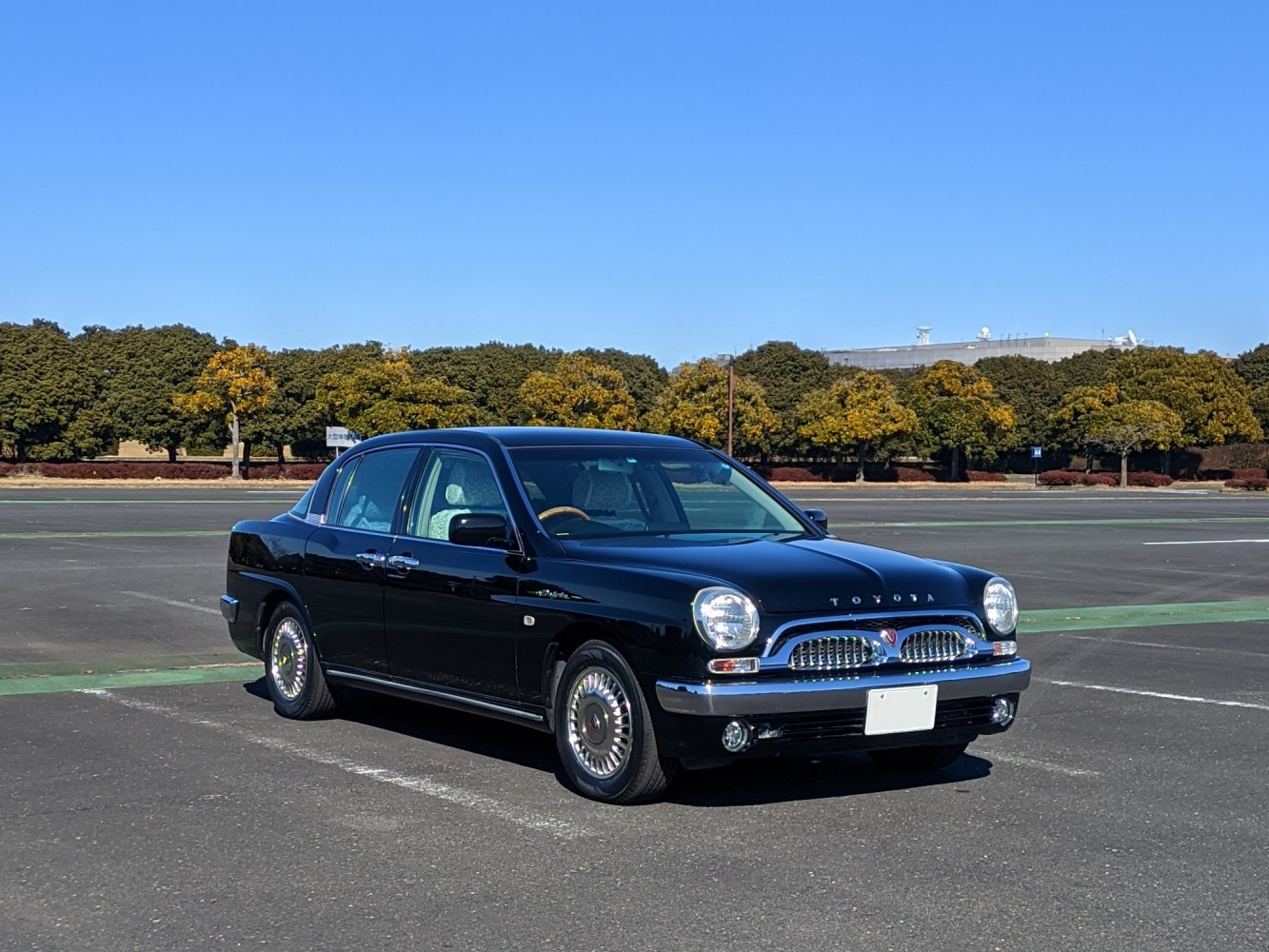 Black sedan with retro chrome grille and round headlights under clear blue sky