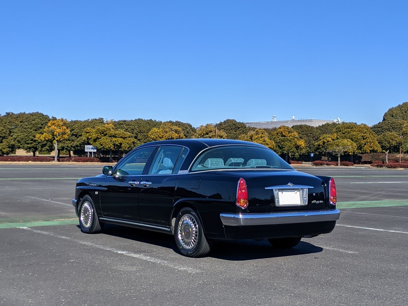 Rear side profile of a black vintage-style sedan with chrome accents and classic vertical taillights
