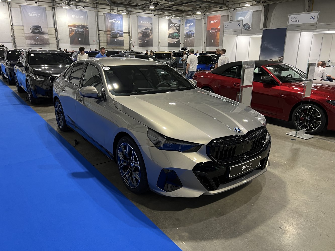 Silver 2024 sedan with kidney grille and alloy wheels indoors