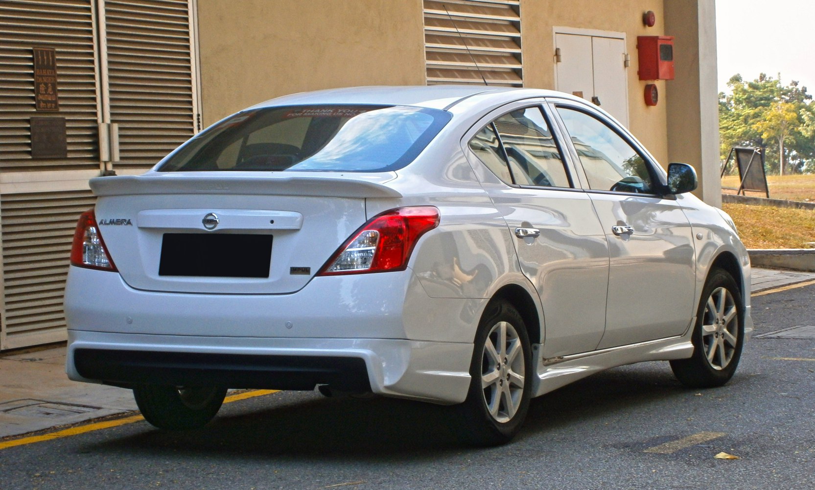 Rear-side view showing spoiler, taillights, alloy wheels, and sedan body.